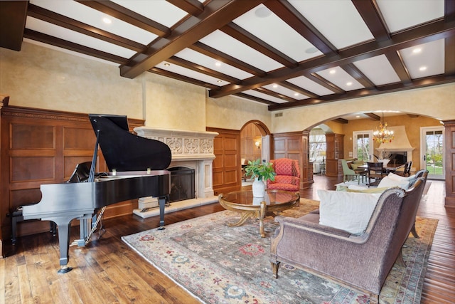 living room with a decorative wall, ornate columns, a high end fireplace, hardwood / wood-style flooring, and arched walkways