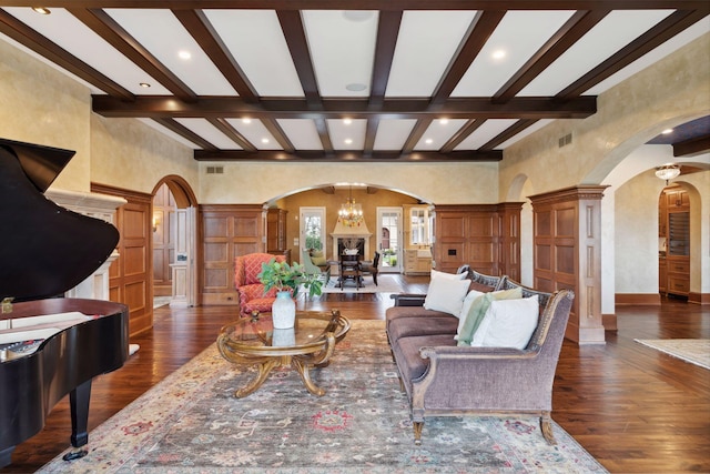 living room with beam ceiling, arched walkways, a chandelier, dark wood-type flooring, and ornate columns