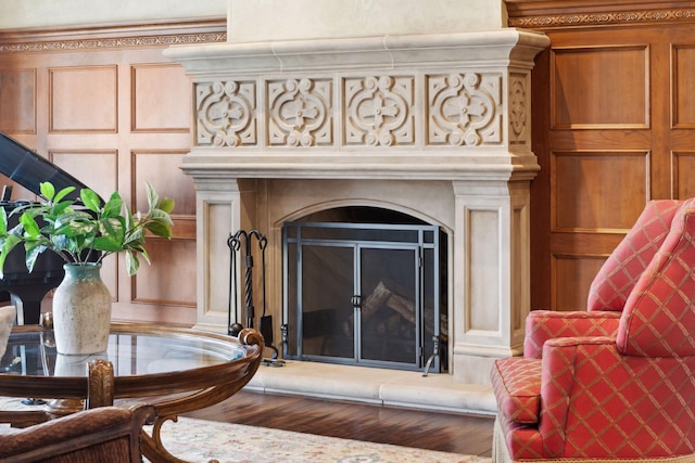 room details with a fireplace with raised hearth, wood finished floors, and a decorative wall