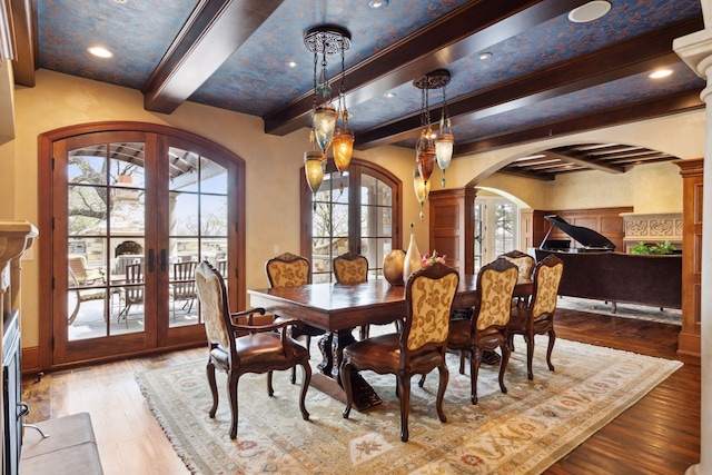 dining room featuring arched walkways, beamed ceiling, french doors, and hardwood / wood-style floors