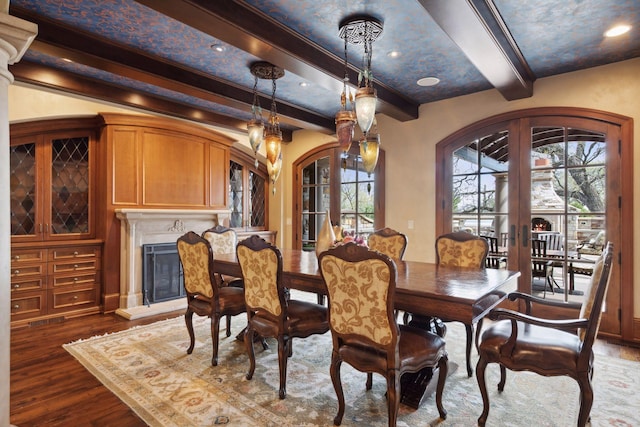 dining space featuring dark wood-type flooring, arched walkways, plenty of natural light, and beam ceiling