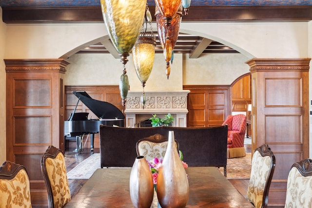 dining room with beam ceiling, a decorative wall, arched walkways, a wainscoted wall, and hardwood / wood-style floors
