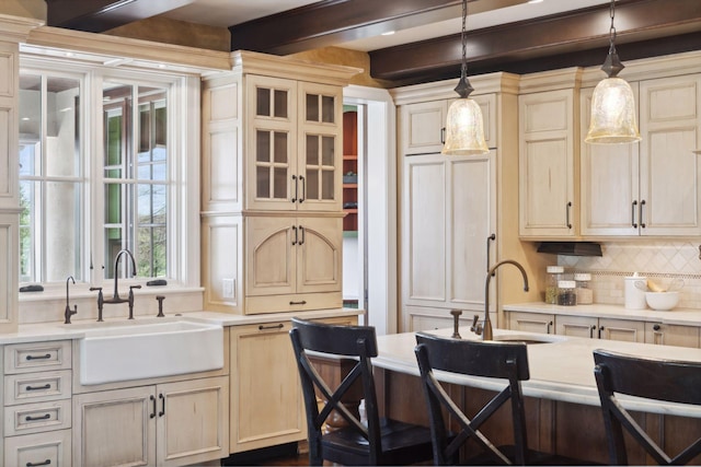 kitchen with light countertops, beam ceiling, a sink, and tasteful backsplash