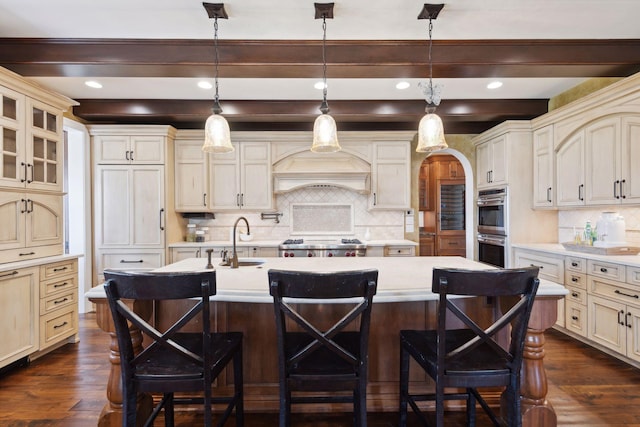 kitchen featuring light countertops, cream cabinets, a sink, backsplash, and stainless steel appliances