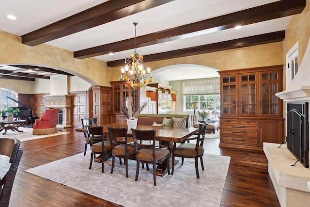 dining space featuring a fireplace, beamed ceiling, dark wood-type flooring, arched walkways, and a notable chandelier