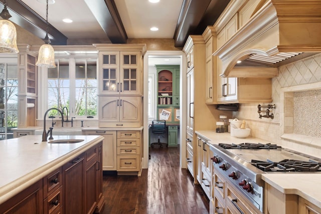 kitchen with a sink, light countertops, premium range hood, stainless steel gas stovetop, and dark wood-style floors