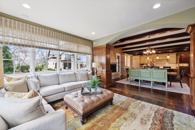 living room featuring an inviting chandelier, beam ceiling, arched walkways, recessed lighting, and dark wood-style floors