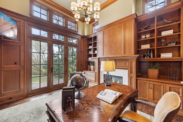 office space featuring built in shelves, a chandelier, a healthy amount of sunlight, and french doors