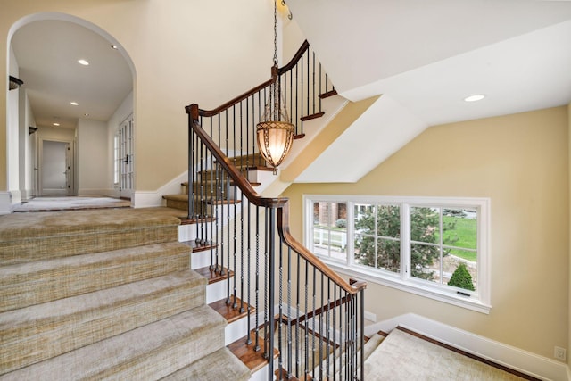 staircase with arched walkways, baseboards, recessed lighting, and wood finished floors