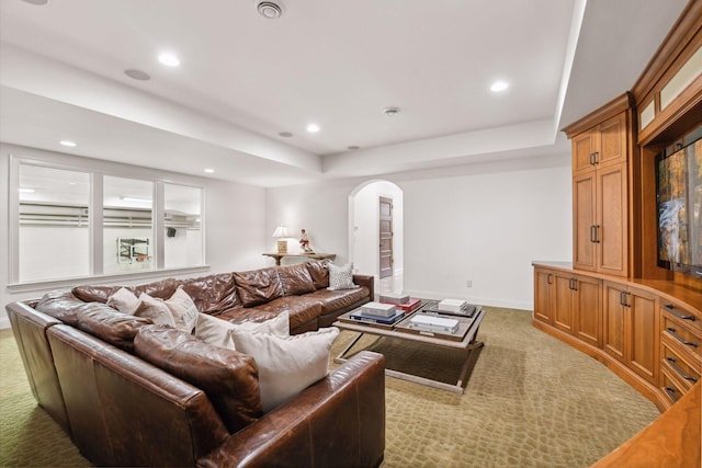living area featuring arched walkways, baseboards, a raised ceiling, carpet, and recessed lighting