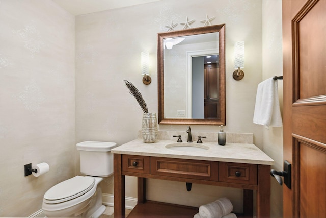 half bath with vanity, baseboards, and toilet