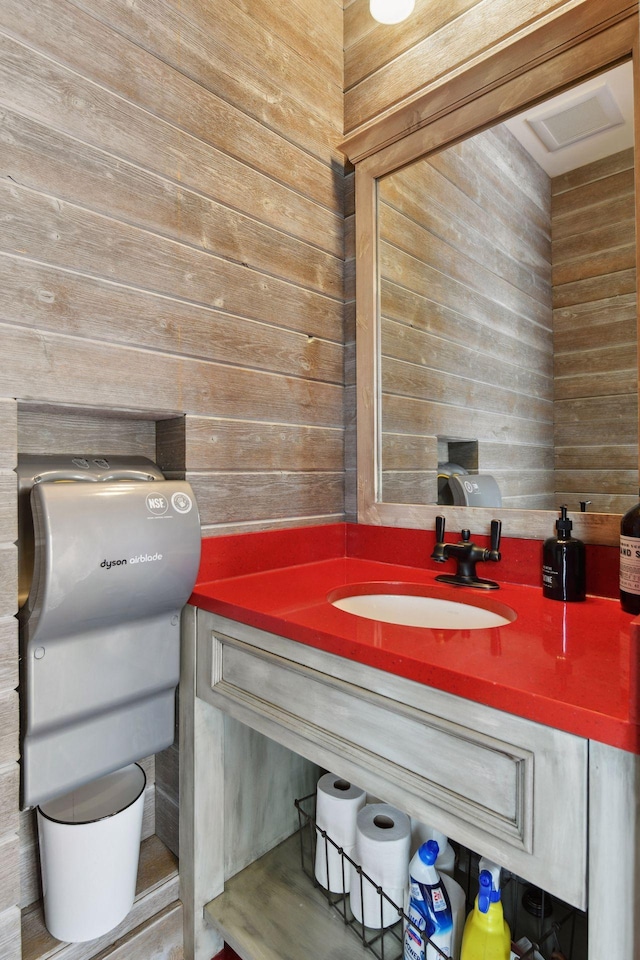 bathroom featuring vanity and wooden walls
