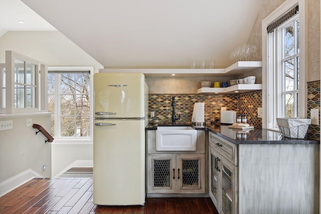 kitchen with freestanding refrigerator, dark countertops, dark wood finished floors, and tasteful backsplash