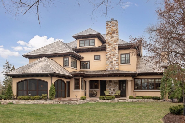 view of front of house with stucco siding, a chimney, and a front yard