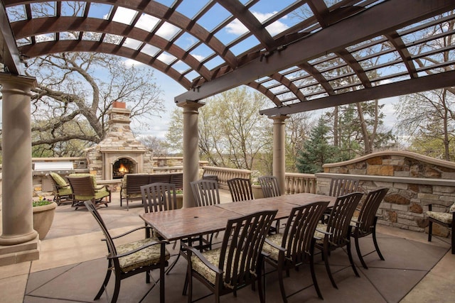 view of patio / terrace featuring outdoor dining area, a stone fireplace, and a pergola