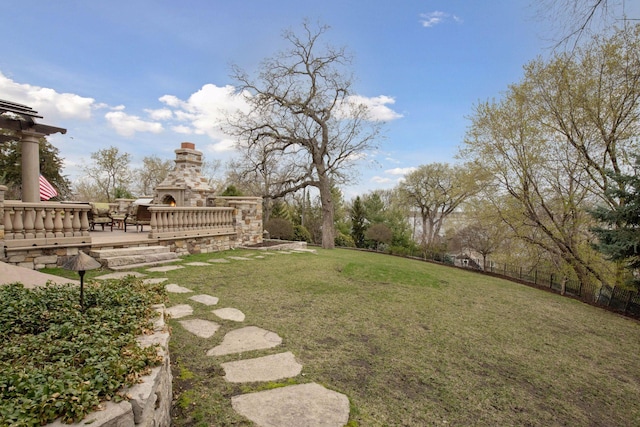 view of yard featuring fence, a patio area, and an outdoor stone fireplace