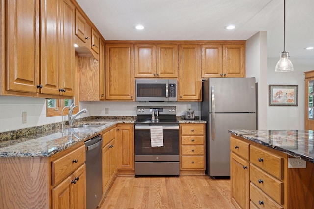 220 Willow Ln, Foley, MN 56329 - kitchen with appliances with stainless steel finishes, dark stone counters, light wood-style floors, brown cabinetry, and recessed lighting