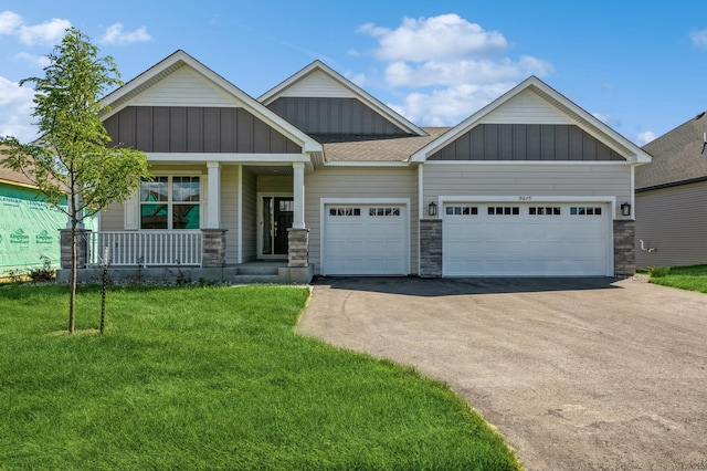 craftsman-style house with a front yard, board and batten siding, an attached garage, driveway, and a porch