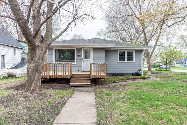 view of front of house with a shingled roof, a front lawn, and a wooden deck