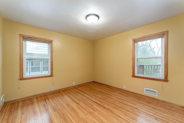 spare room with baseboards, a wealth of natural light, and light wood-style floors