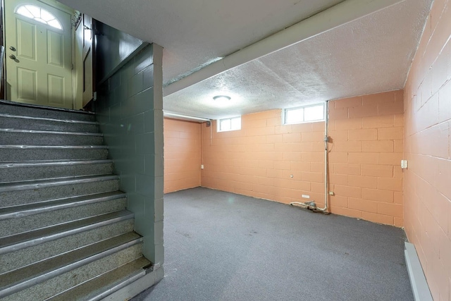 basement with carpet flooring, concrete block wall, a textured ceiling, a baseboard radiator, and stairway