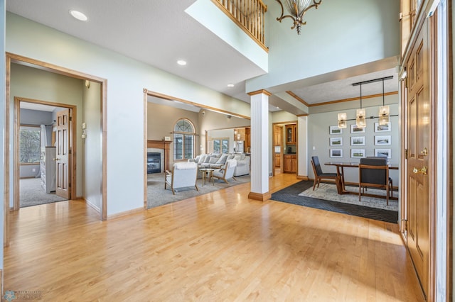 interior space featuring light wood-style floors, baseboards, a glass covered fireplace, and recessed lighting