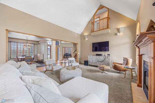 living room featuring light colored carpet, a glass covered fireplace, stairway, and high vaulted ceiling