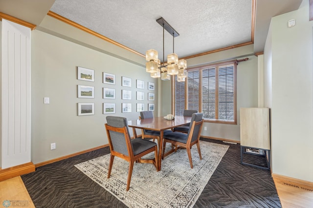 dining area with crown molding, a textured ceiling, baseboards, and a notable chandelier