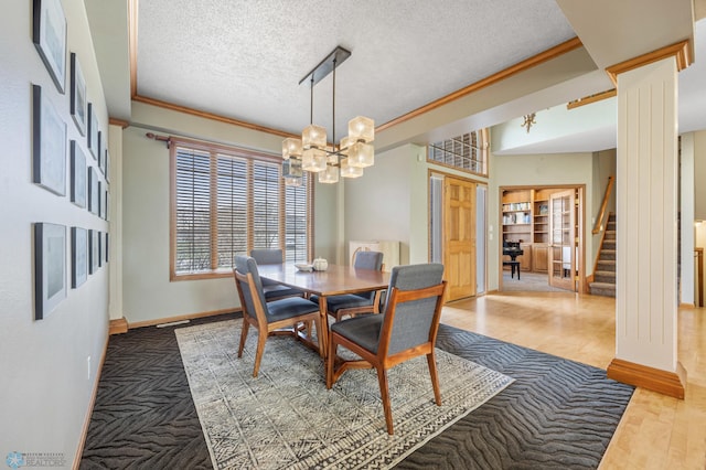 dining room featuring a textured ceiling, stairway, baseboards, a chandelier, and ornamental molding