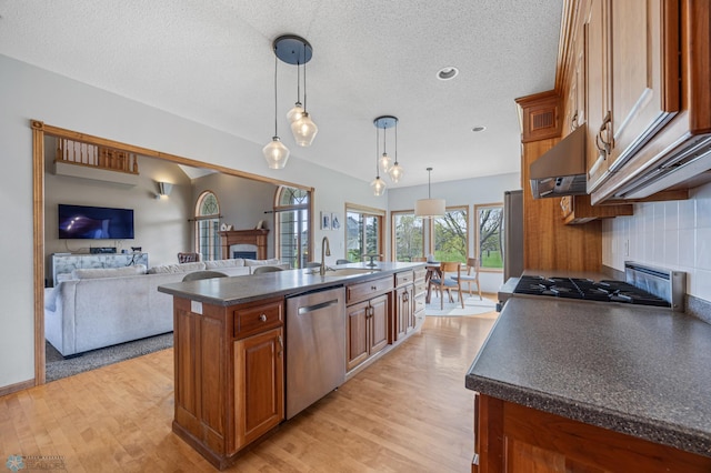 kitchen featuring brown cabinetry, dark countertops, a fireplace, light wood finished floors, and dishwasher