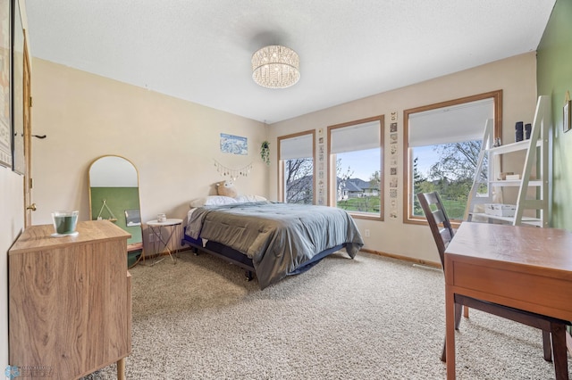 carpeted bedroom featuring an inviting chandelier and baseboards