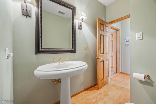 bathroom with baseboards, visible vents, and wood finished floors