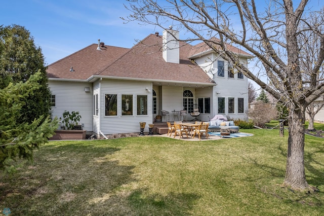 back of property with roof with shingles, a patio, a chimney, and a yard