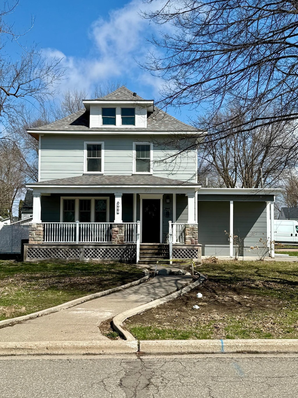traditional style home with roof with shingles and a porch