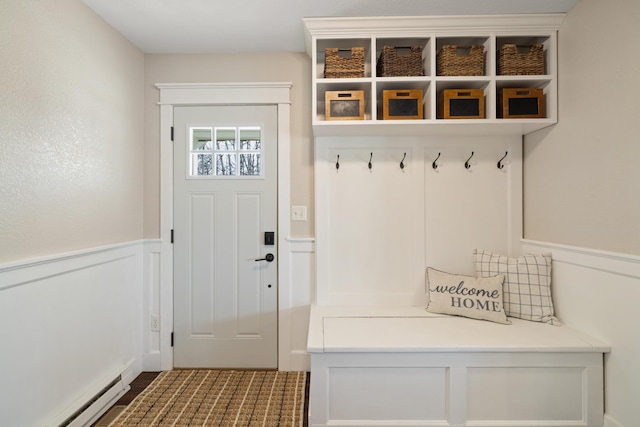 mudroom featuring wainscoting, baseboard heating, and a decorative wall