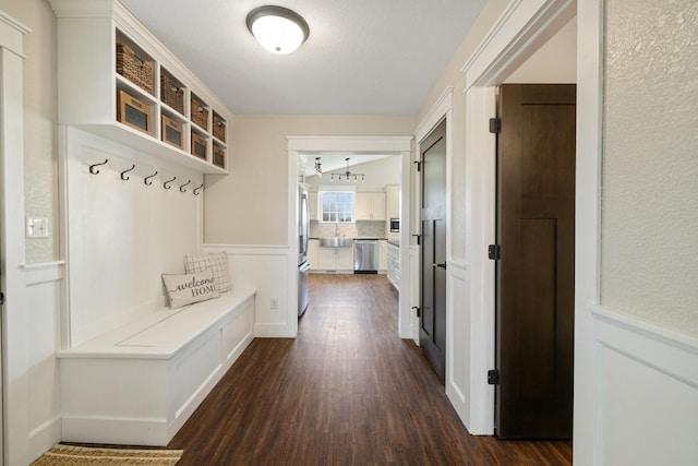 mudroom featuring a decorative wall, dark wood finished floors, and a wainscoted wall