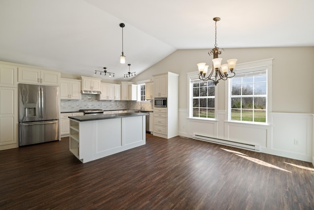 kitchen featuring a healthy amount of sunlight, dark countertops, a baseboard radiator, appliances with stainless steel finishes, and a notable chandelier