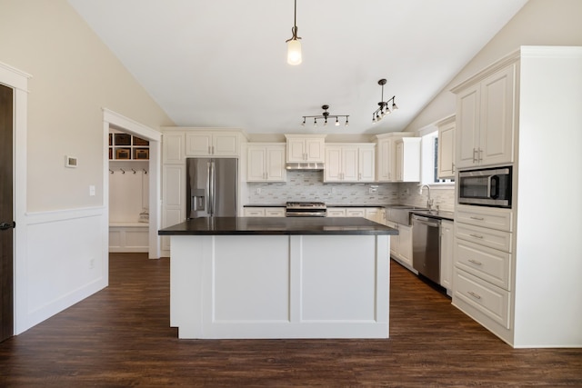 kitchen with appliances with stainless steel finishes, a sink, decorative backsplash, a kitchen island, and vaulted ceiling