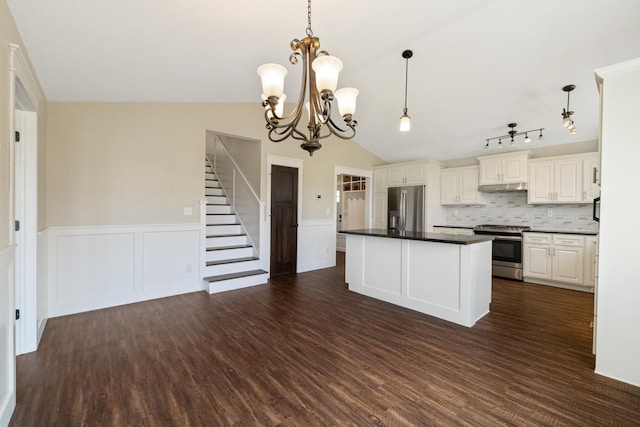 kitchen featuring a center island, a wainscoted wall, dark countertops, and stainless steel appliances
