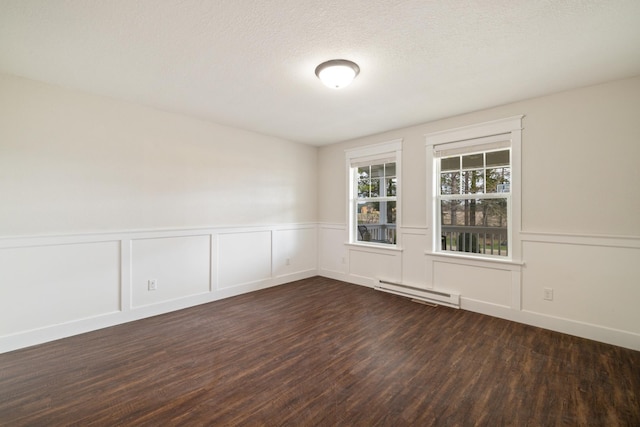 spare room featuring wainscoting, a decorative wall, a baseboard heating unit, and dark wood-style flooring