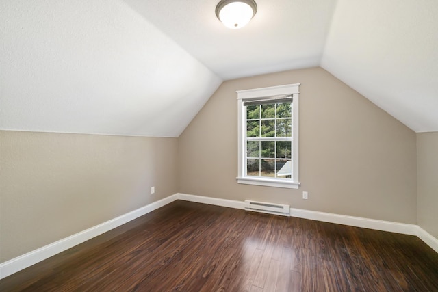 additional living space featuring vaulted ceiling, baseboards, a baseboard heating unit, and dark wood-type flooring