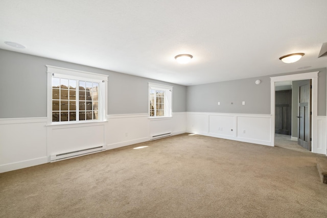 carpeted empty room with wainscoting, a wealth of natural light, and a baseboard radiator