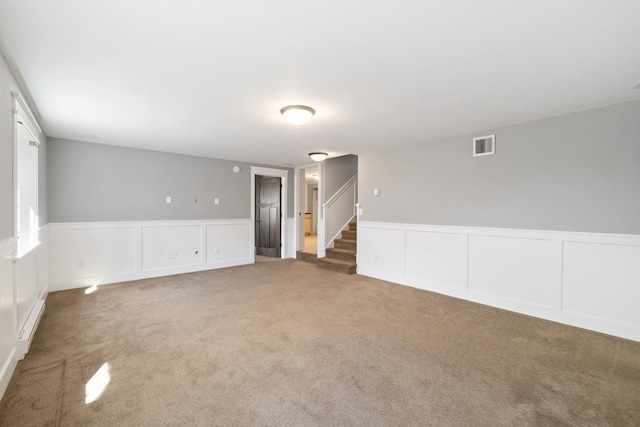 spare room with stairs, visible vents, wainscoting, and carpet