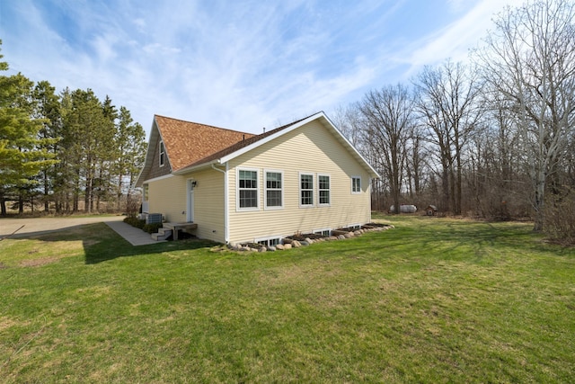 view of home's exterior with a lawn and roof with shingles