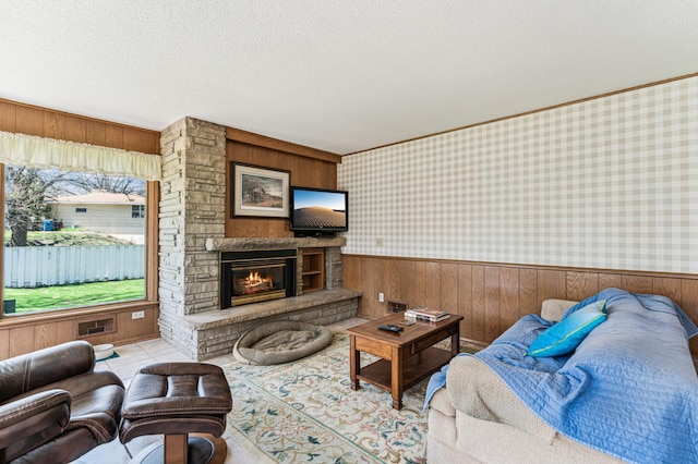 living room with a textured ceiling, wood walls, a wainscoted wall, and a fireplace