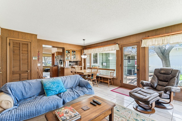 living area with wooden walls, a textured ceiling, and light tile patterned floors