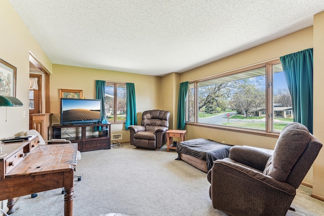 living area with a healthy amount of sunlight, carpet flooring, a textured ceiling, and visible vents