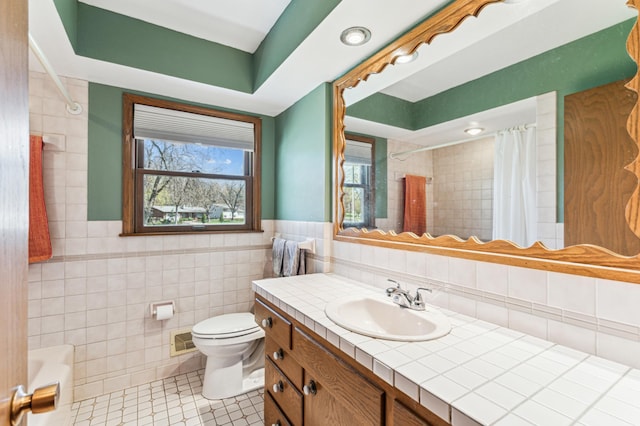 bathroom with vanity, toilet, tile patterned floors, tile walls, and a shower with curtain