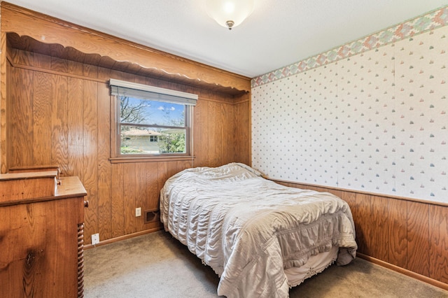 carpeted bedroom featuring baseboards, wood walls, and wallpapered walls