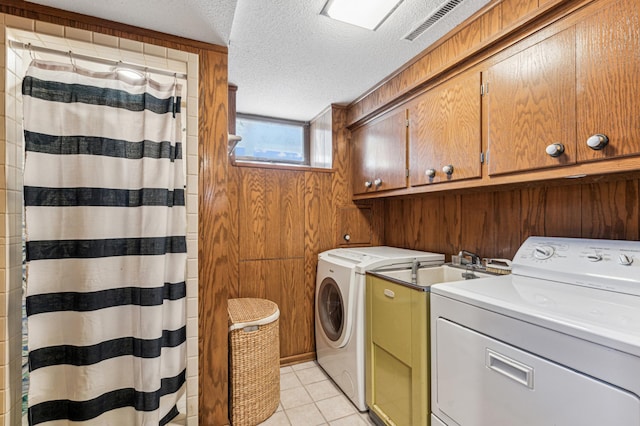 washroom featuring visible vents, wood walls, a textured ceiling, washing machine and clothes dryer, and light tile patterned floors